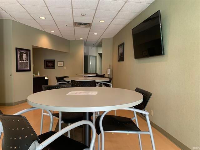 A room with tables and chairs and a flat screen tv on the wall