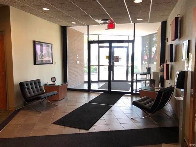 A lobby with a couch and chairs and a red exit sign