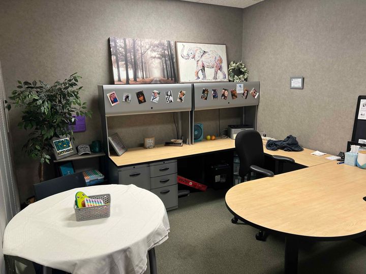 A small office with two desks and a round table.