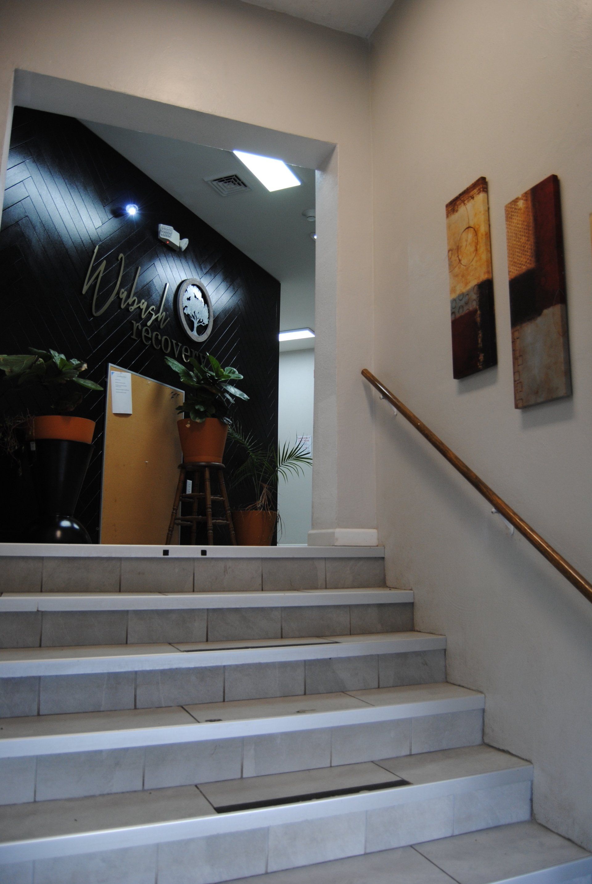 A set of stairs leading up to a room with a clock on the wall