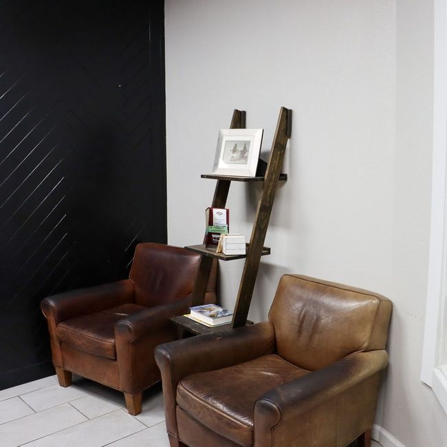 A room with two chairs and a bookshelf with a picture on it