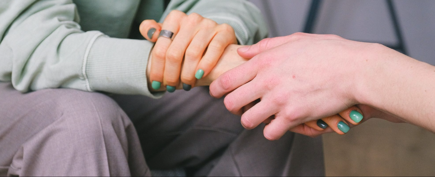 A close up of a person holding another person 's hand.