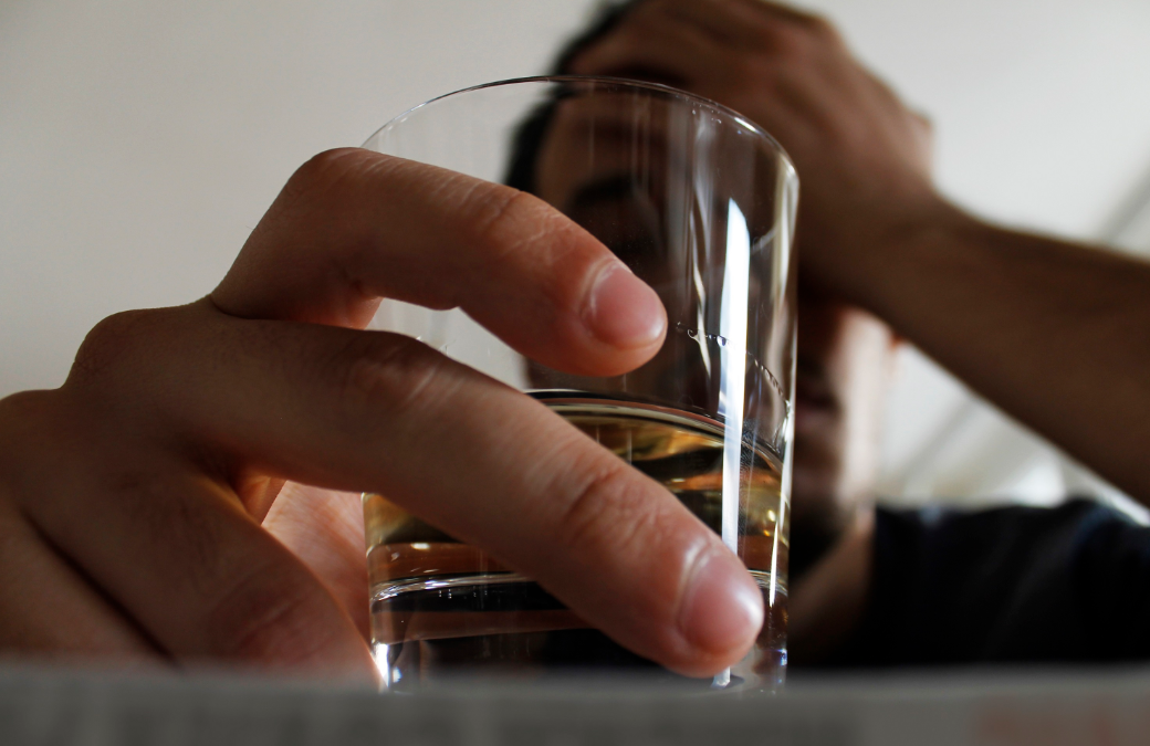 A man is holding a glass of alcohol in his hand