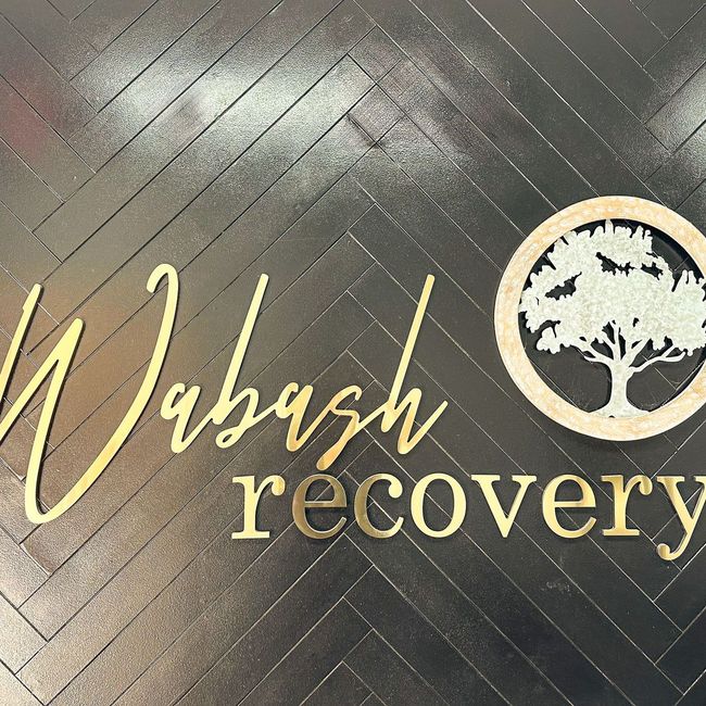 A sign that says wabash recovery with a tree in the middle