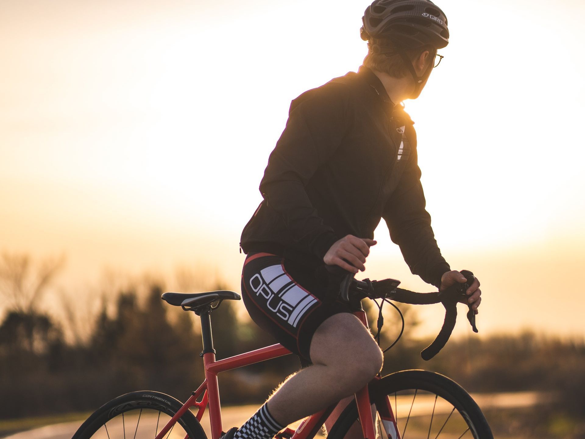 A man is riding a bike on a road at sunset.