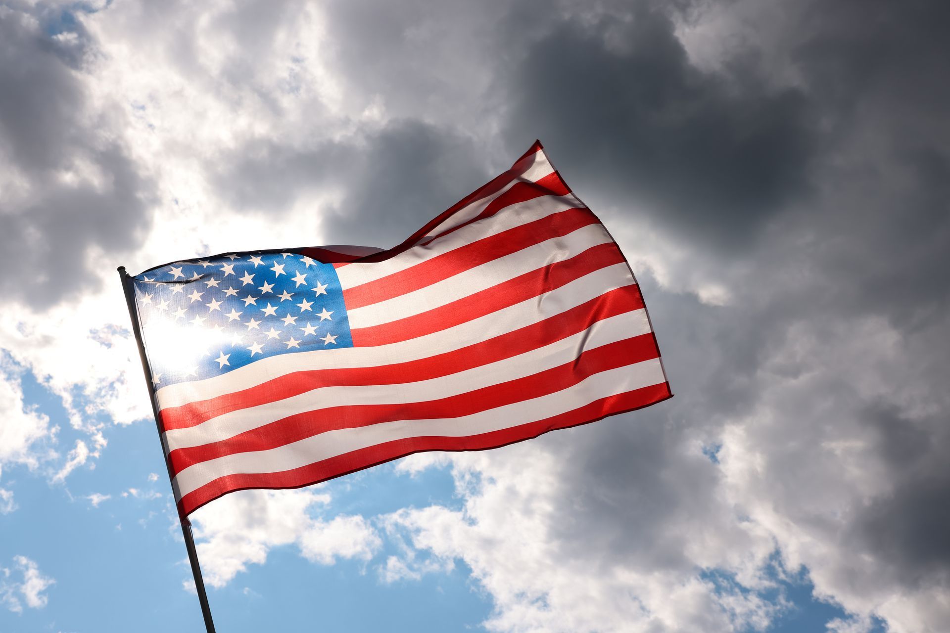 An american flag is waving in the wind against a cloudy sky