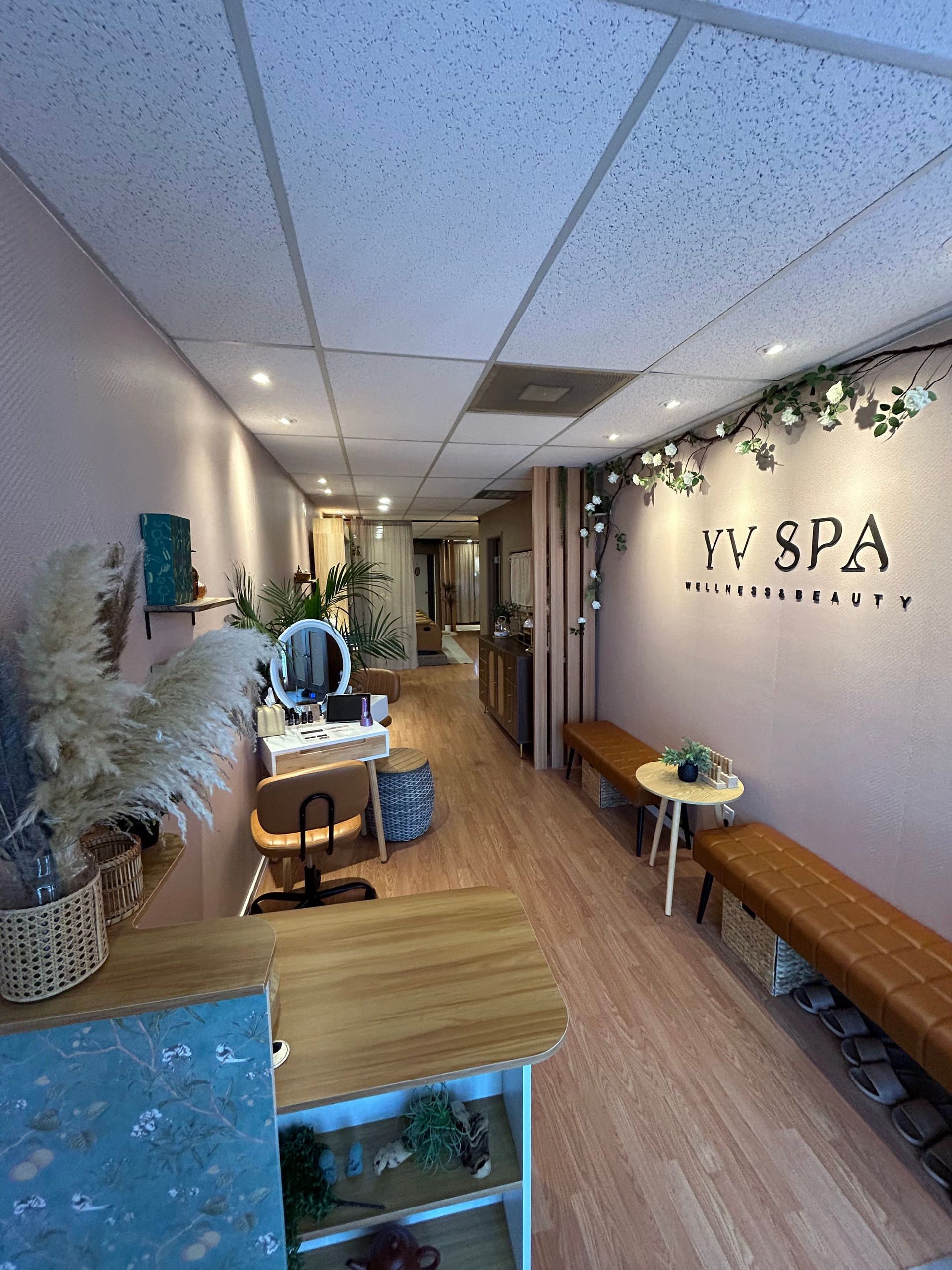 Interior of a spa with pink walls, wooden benches, and plants.