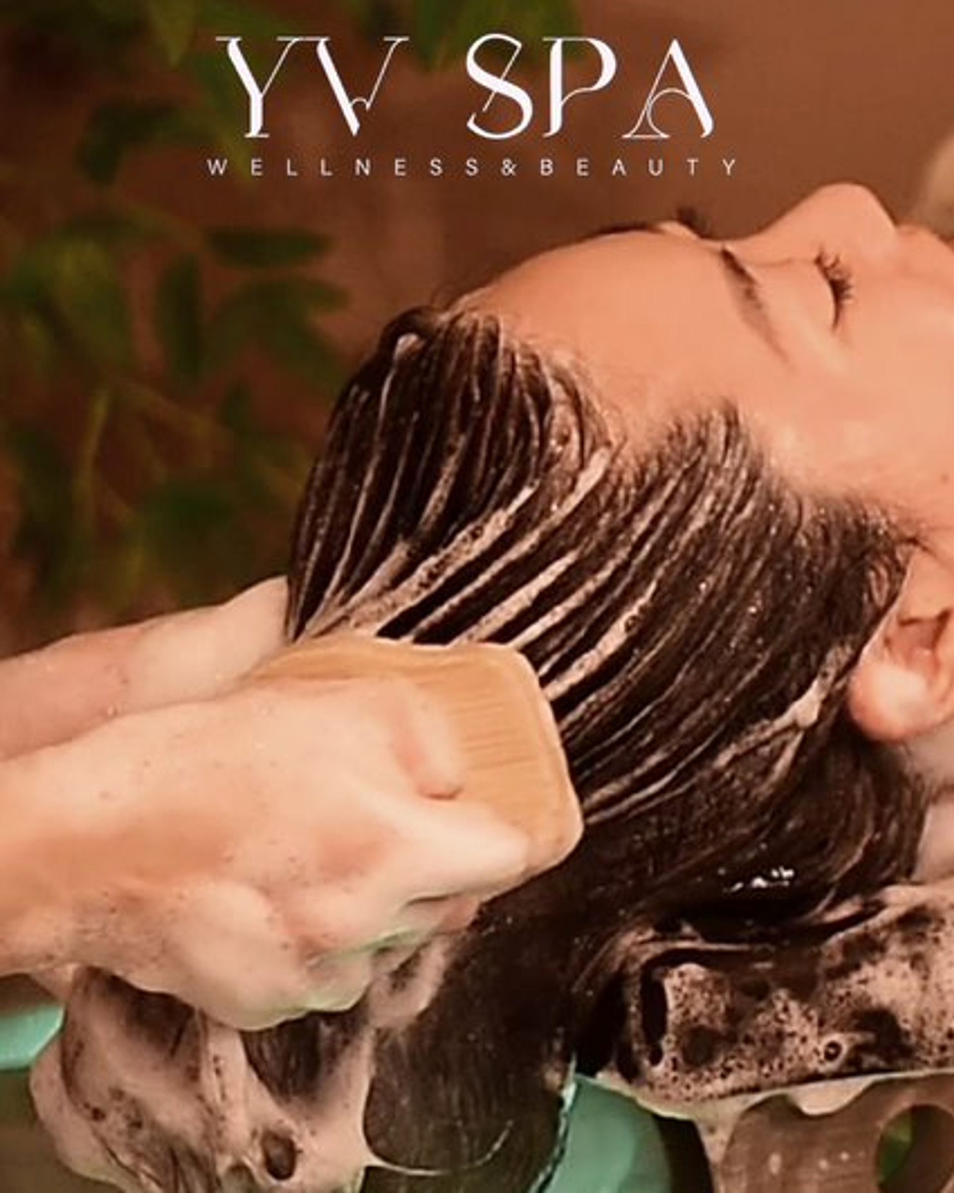 Person getting hair washed at YV SPA, wellness and beauty. Soap lather and wooden tool visible.