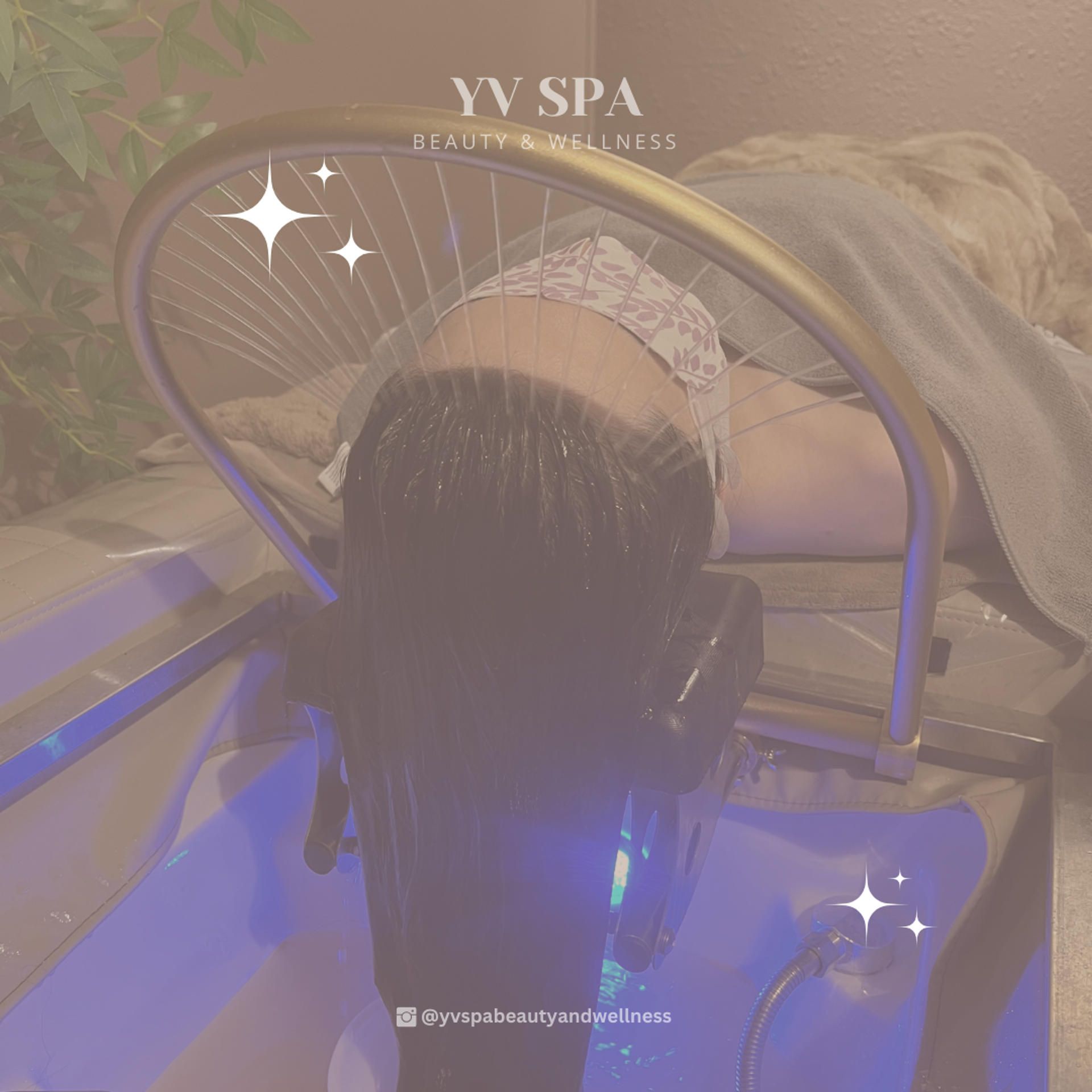 Woman having hair washed at YV Spa. Golden arched wash station. Water cascading over hair.