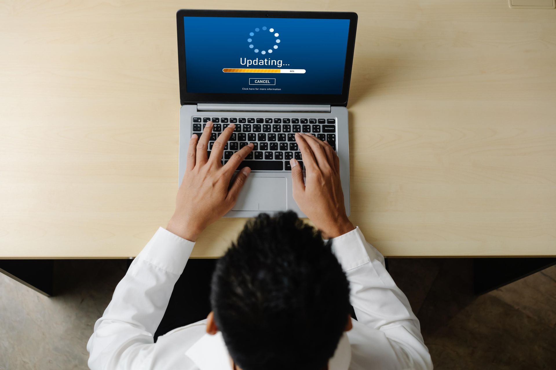 Person working on laptop displaying a software update on a wooden table.