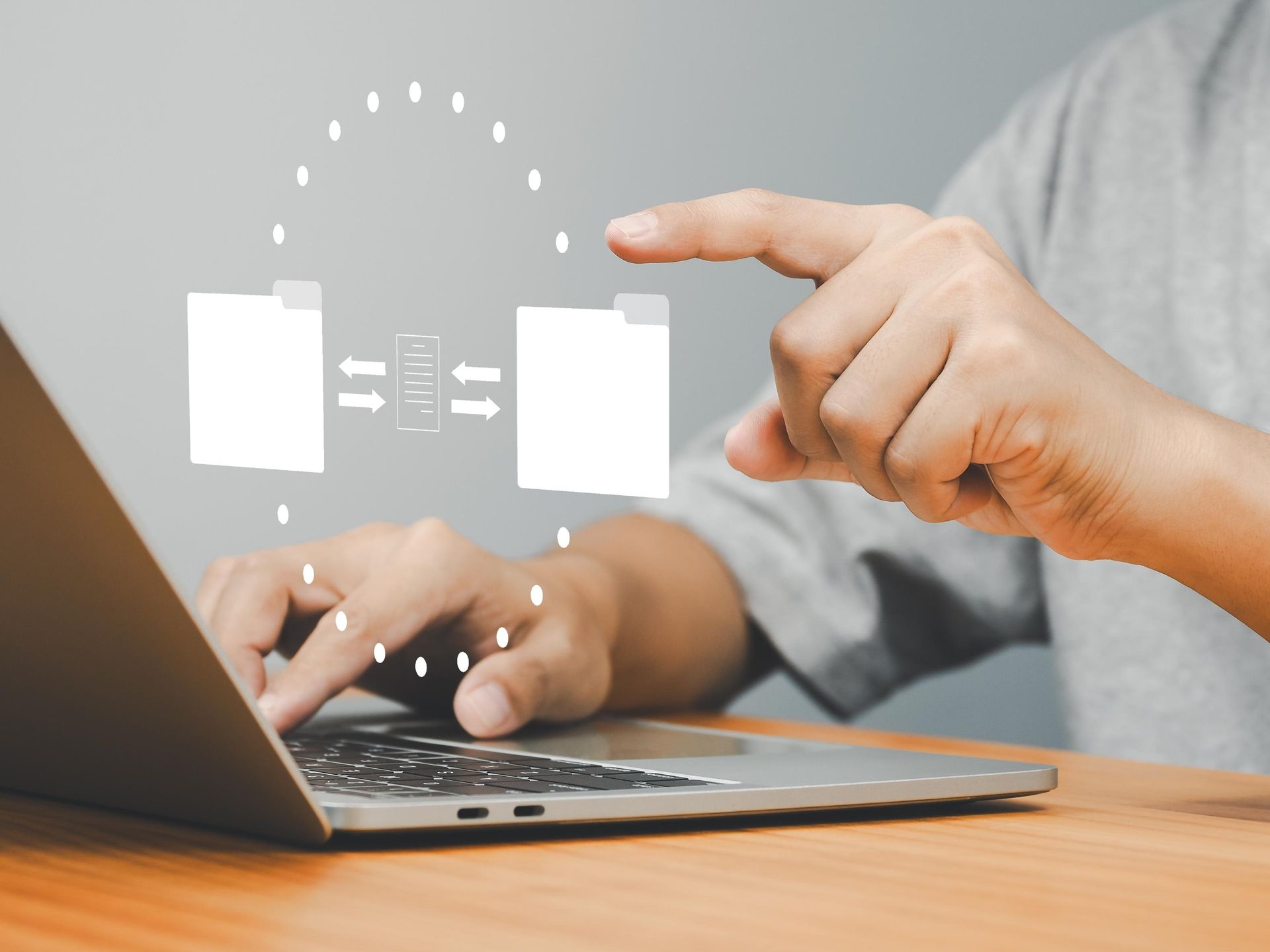 Person using laptop with digital file transfer graphic overlay.