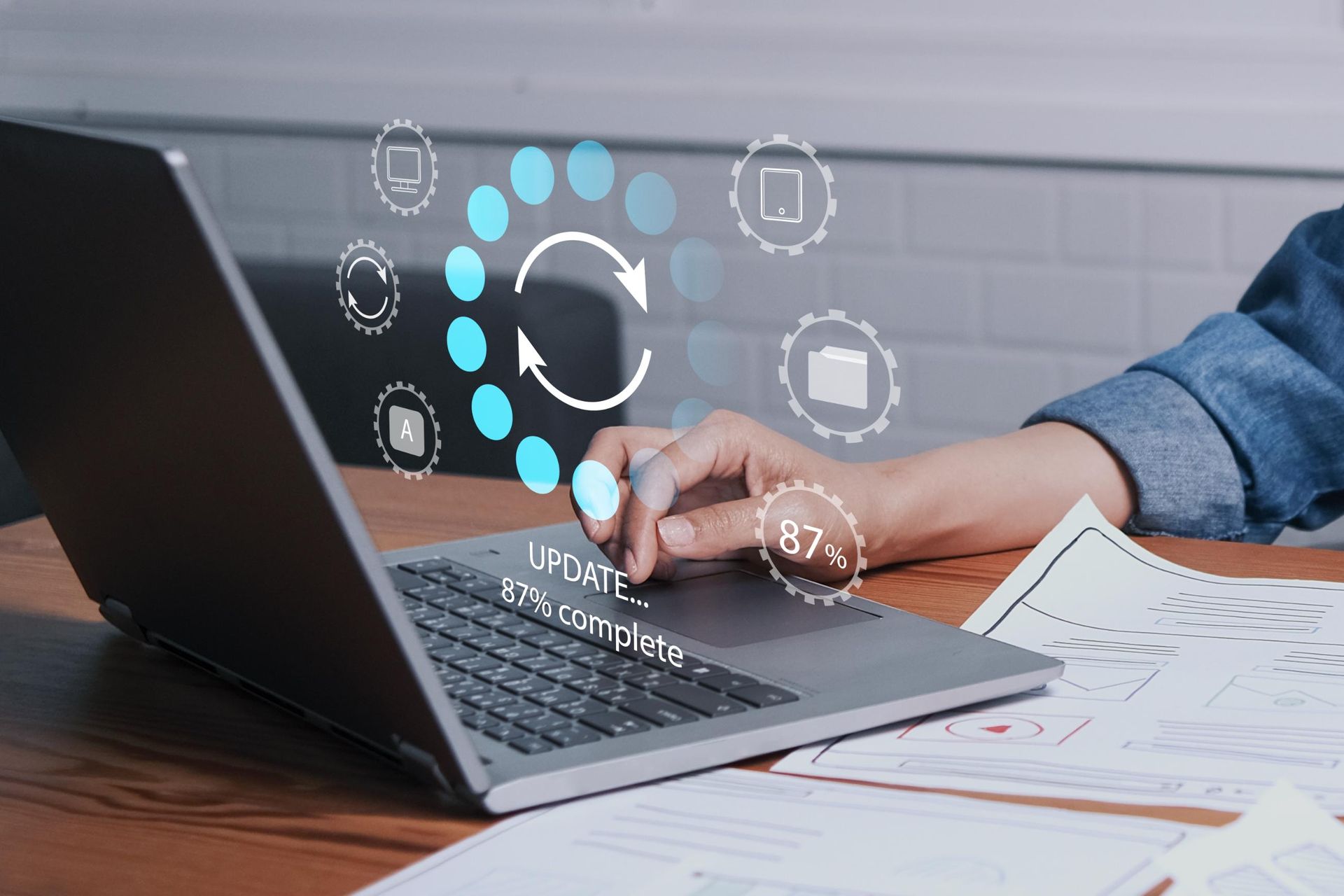 Person updating laptop, loading progress indicator on screen; 87% complete.