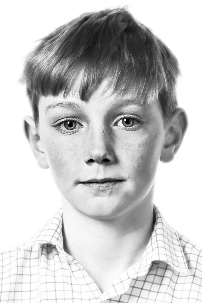 A classical photographic portraiture work, a close up of a young boy in incredible detail, shot in black and white.