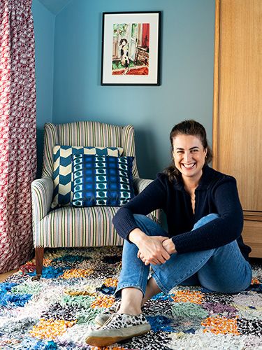 Custom close up fine art photo portrait photography of a woman smiling sitting on a bedroom floor next to a chair.