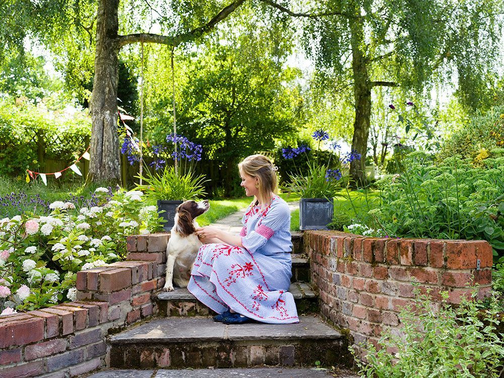 Outdoor photo portrait photograph of a woman sitting in her garden with a dog, professionally edited to enhance the subject.