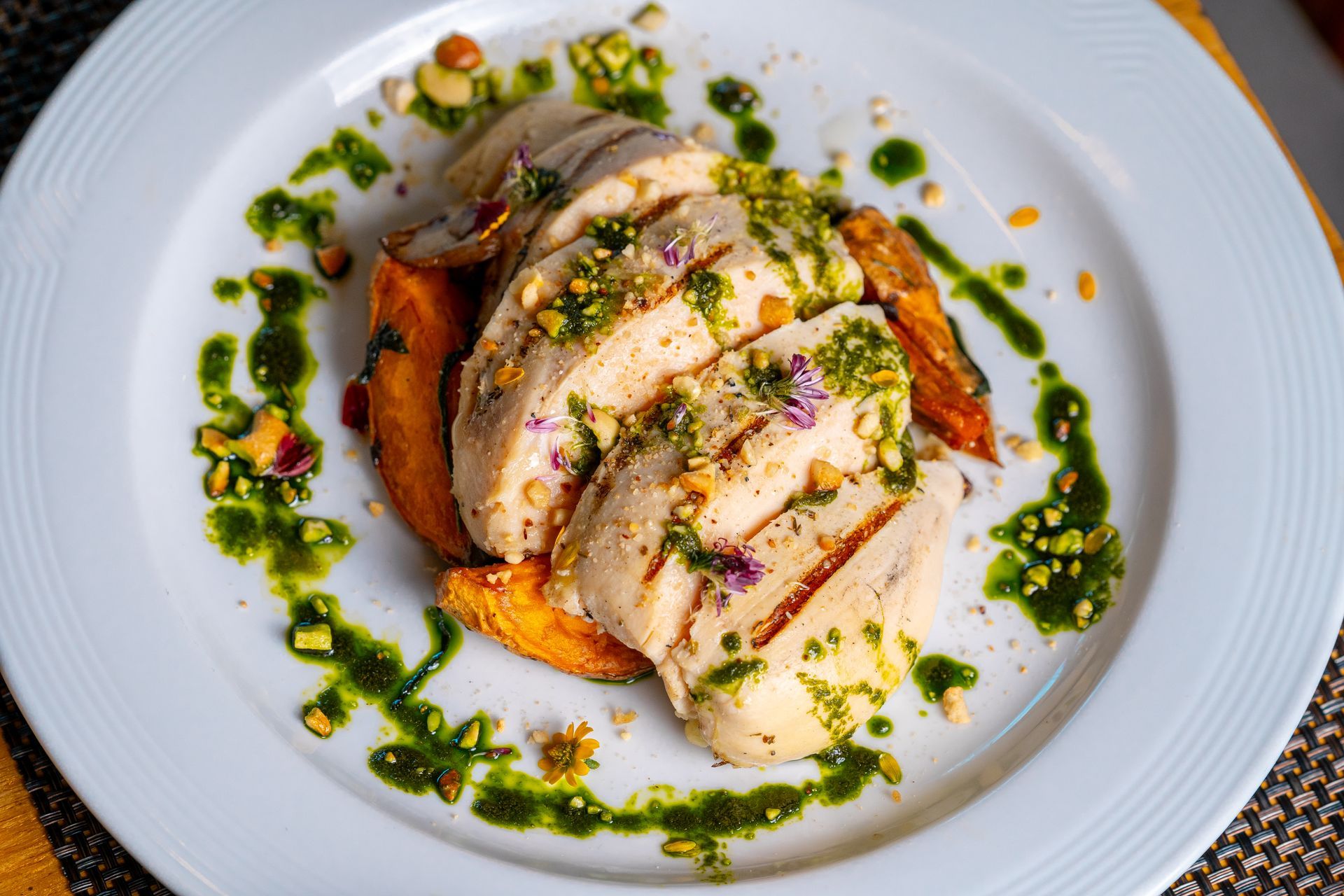 A white plate topped with chicken and vegetables on a table.