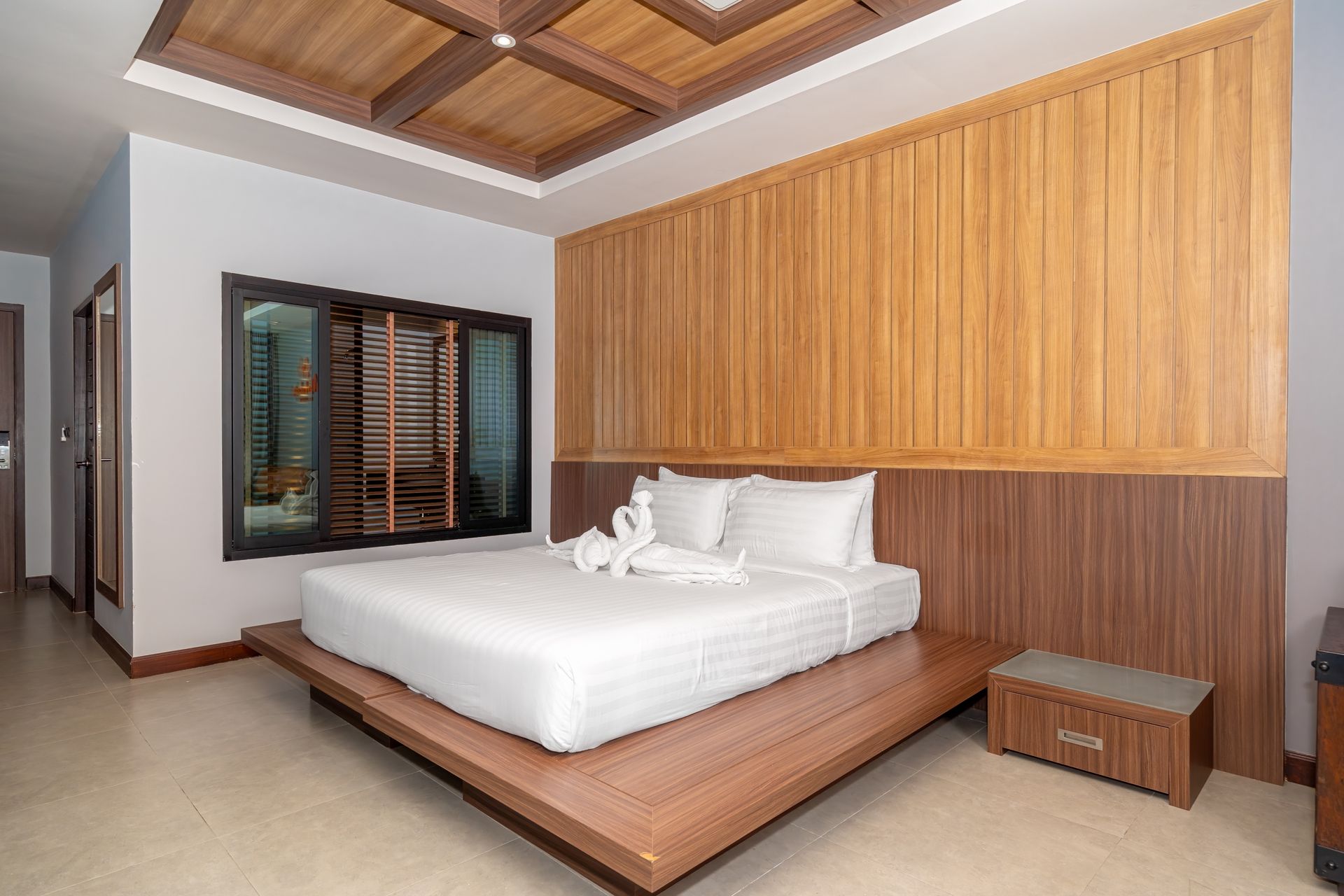 A hotel room with a king size bed and wooden walls.