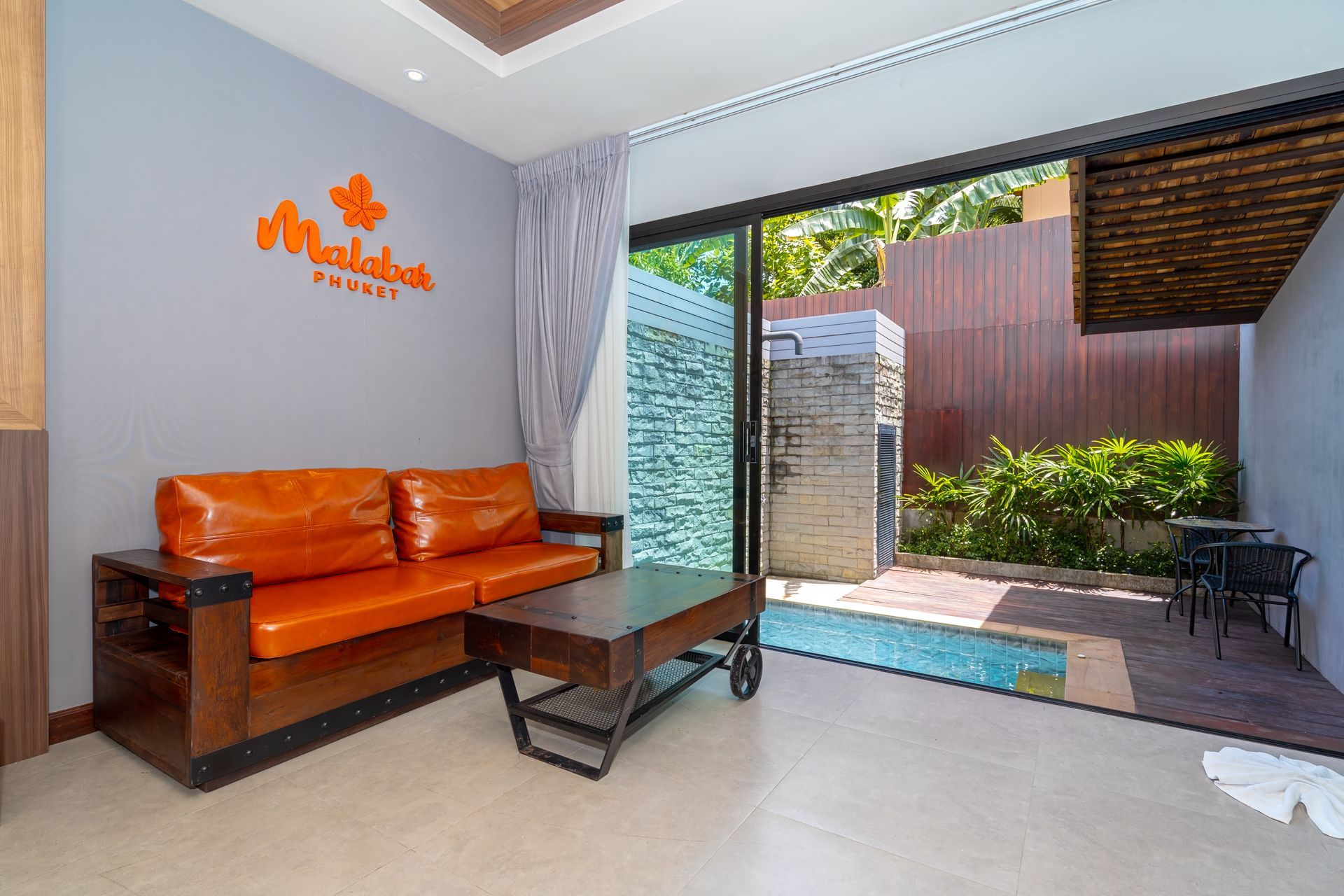 A living room with a couch , table and sliding glass doors leading to a swimming pool.