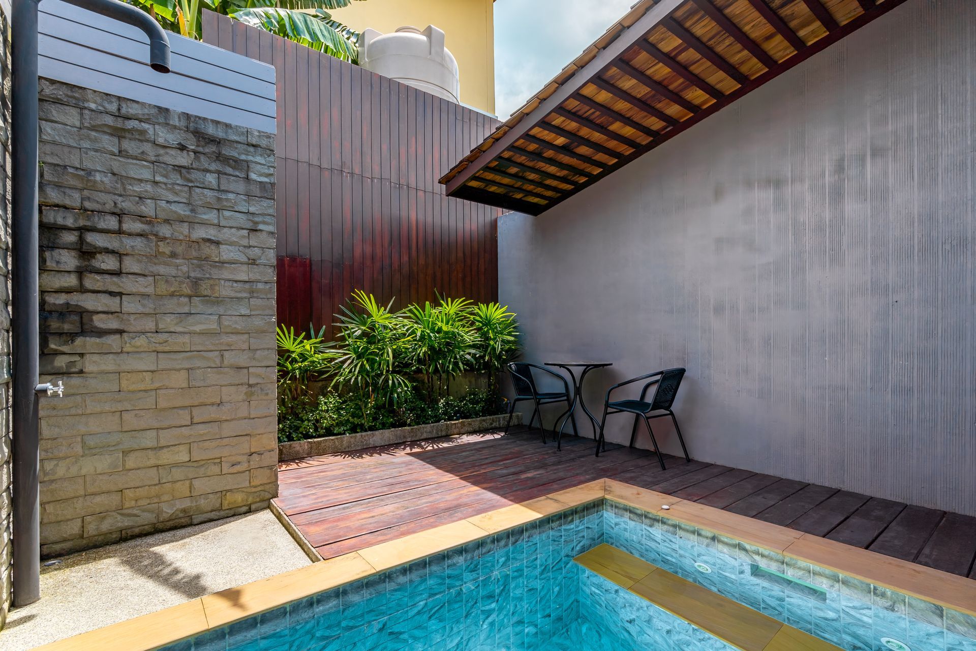 There is a swimming pool with a table and chairs next to it.