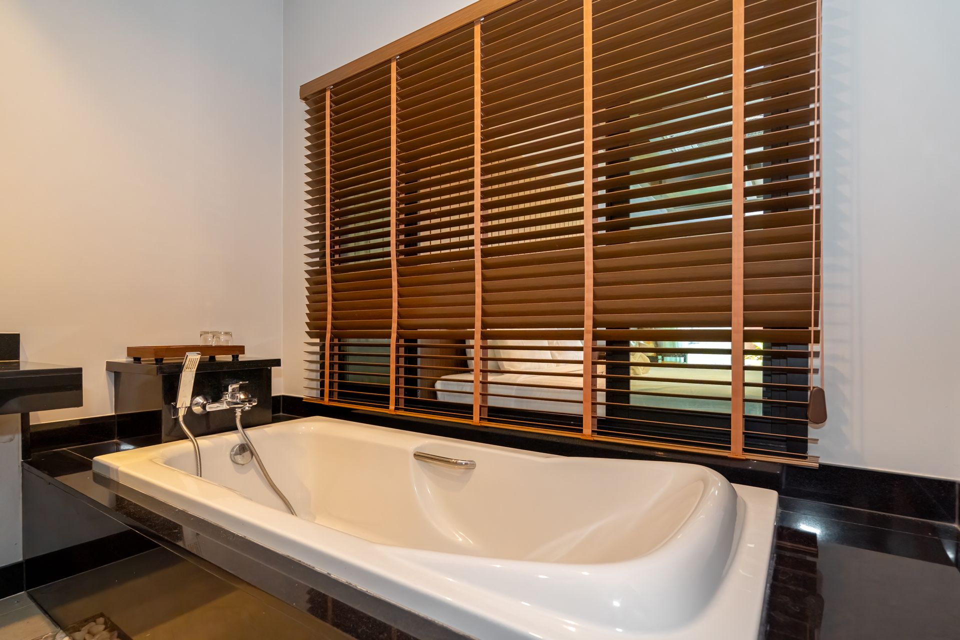 A bathroom with a bathtub and a window with blinds.