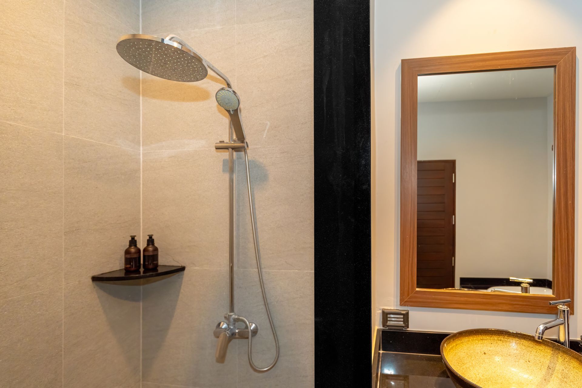 A bathroom with a shower , sink , mirror and shower head.