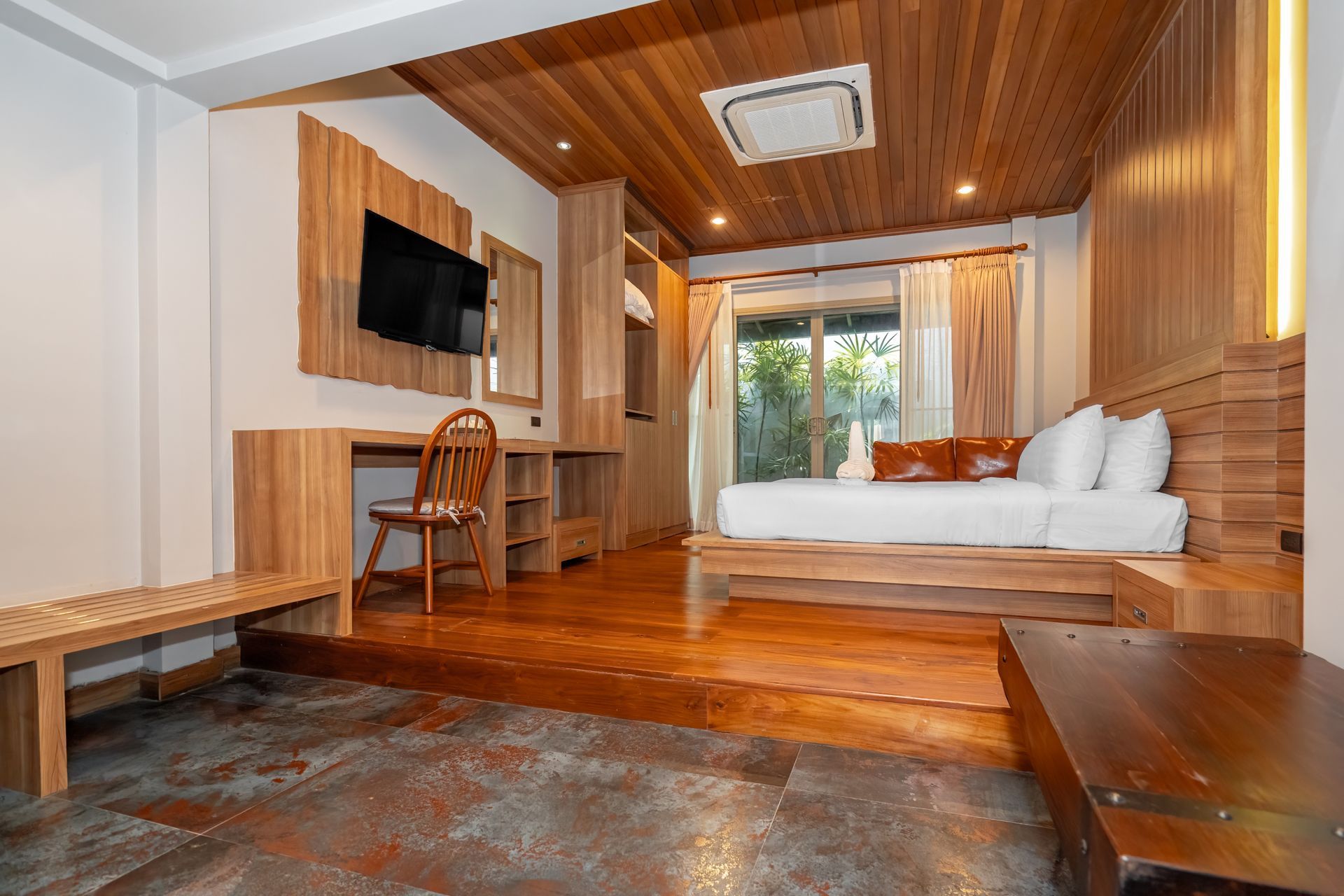 A hotel room with a bed , desk , chair and television.