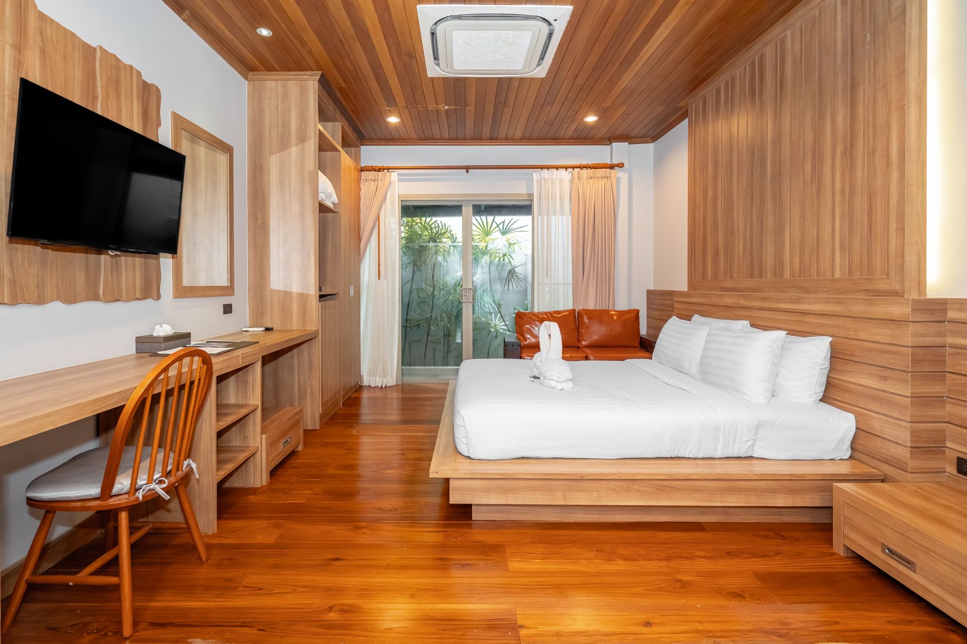 A hotel room with a bed , desk , chair and television.