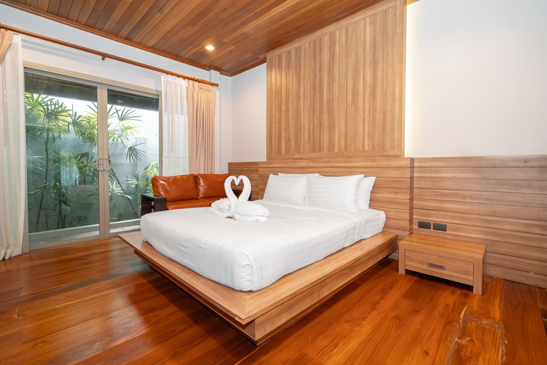 A bedroom with a bed , nightstand , couch and sliding glass door.