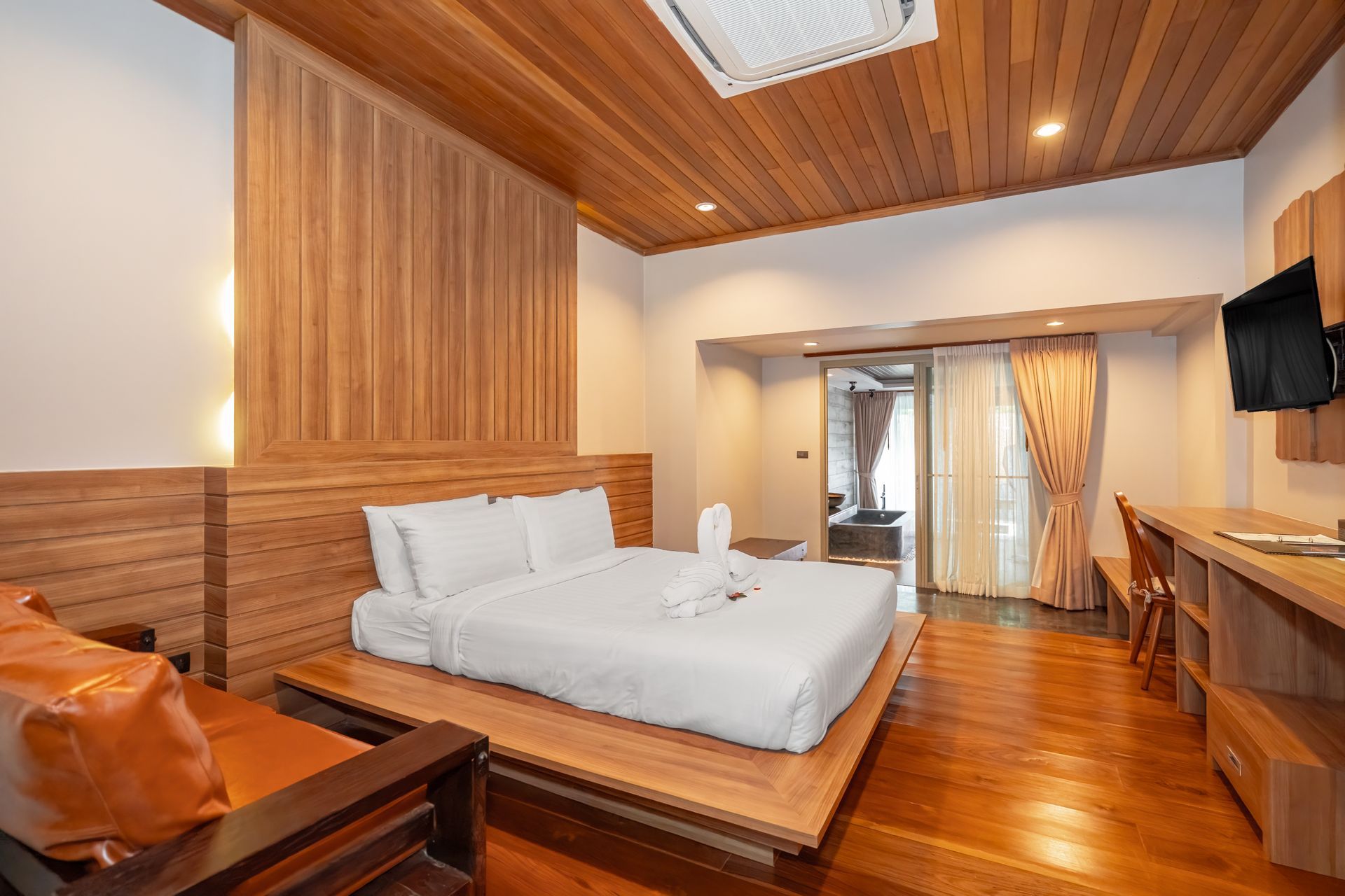 A hotel room with a bed , chair , desk and television.