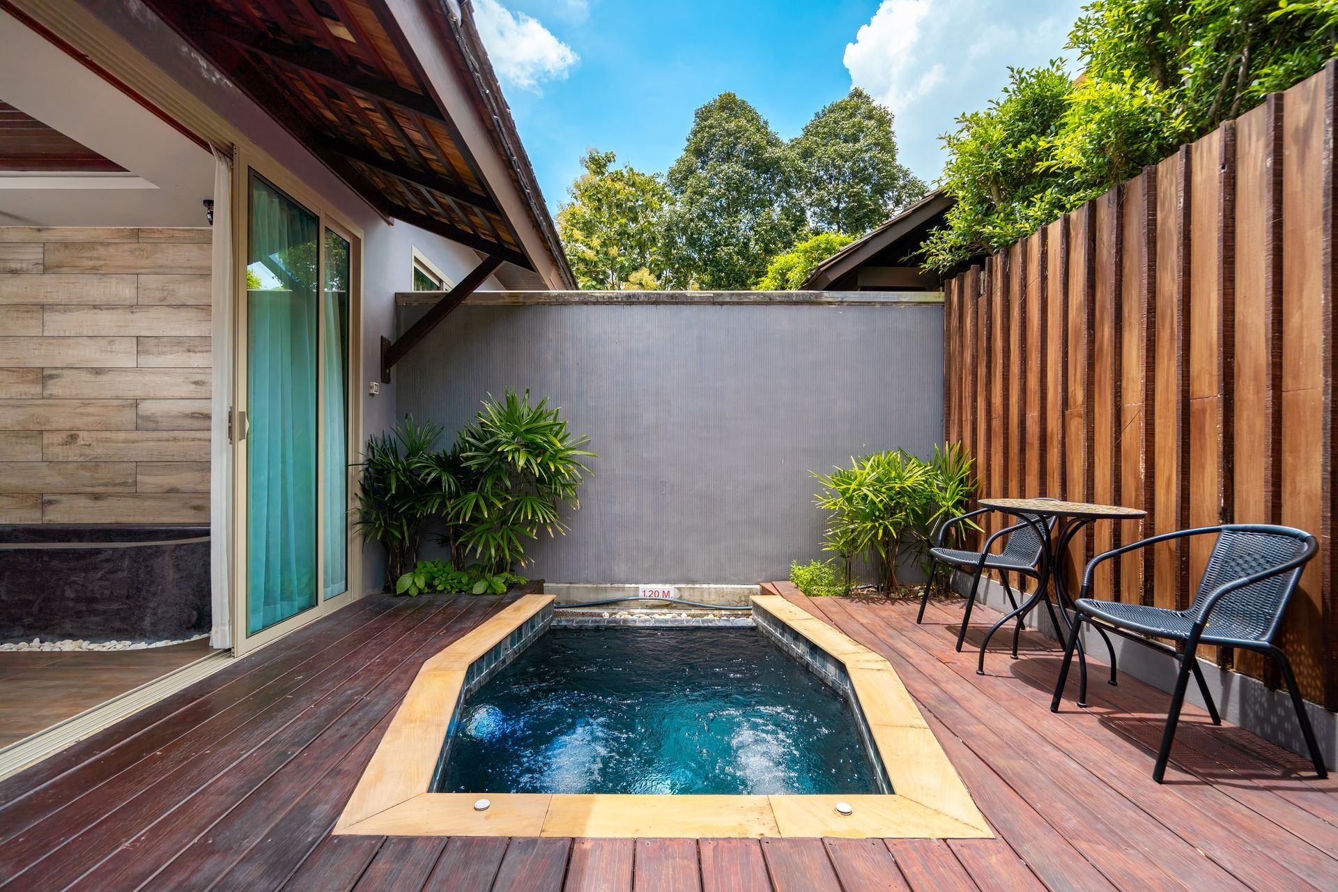 There is a small swimming pool in the backyard of a house.