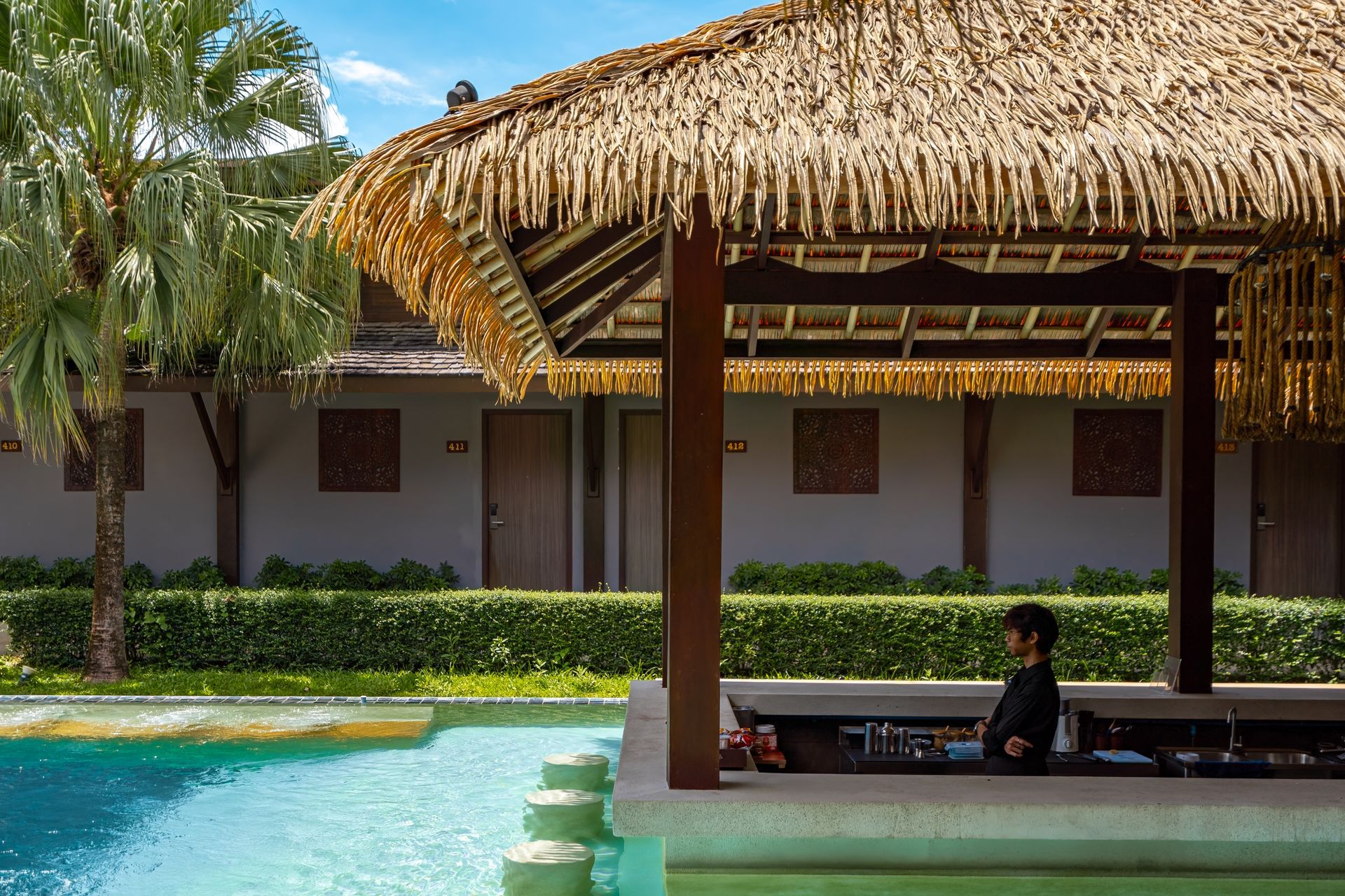 A man is sitting at a bar next to a swimming pool.