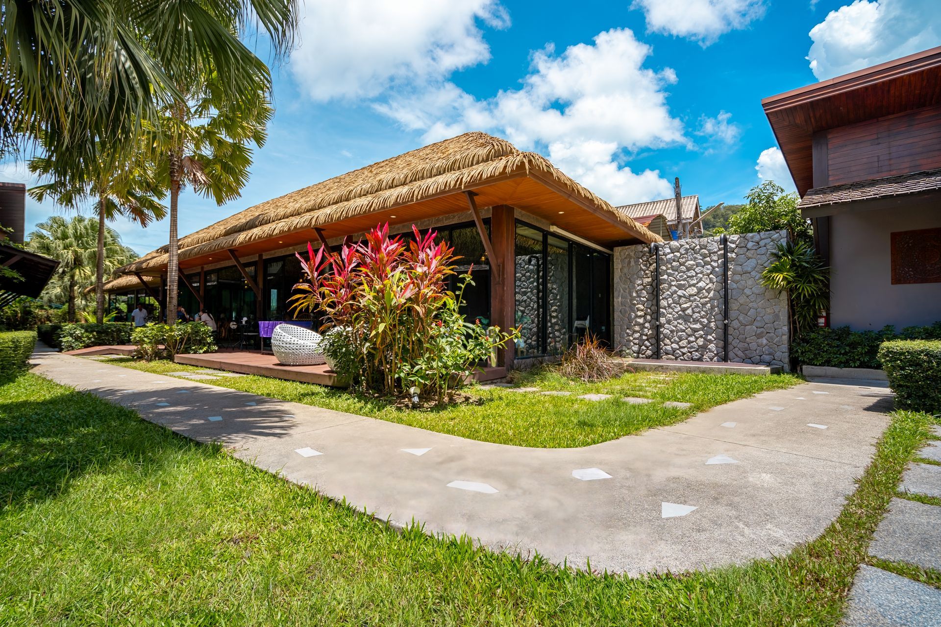 A house with a thatched roof is surrounded by a lush green lawn.