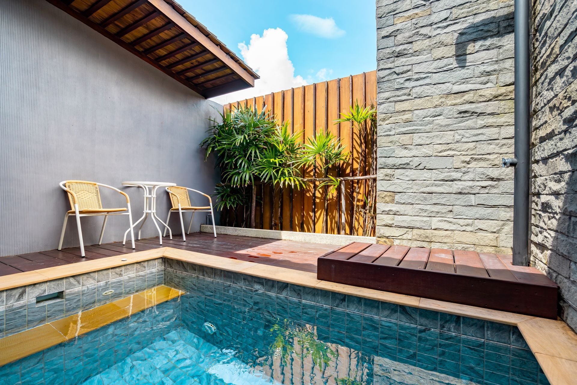 A small swimming pool with a table and chairs next to it.