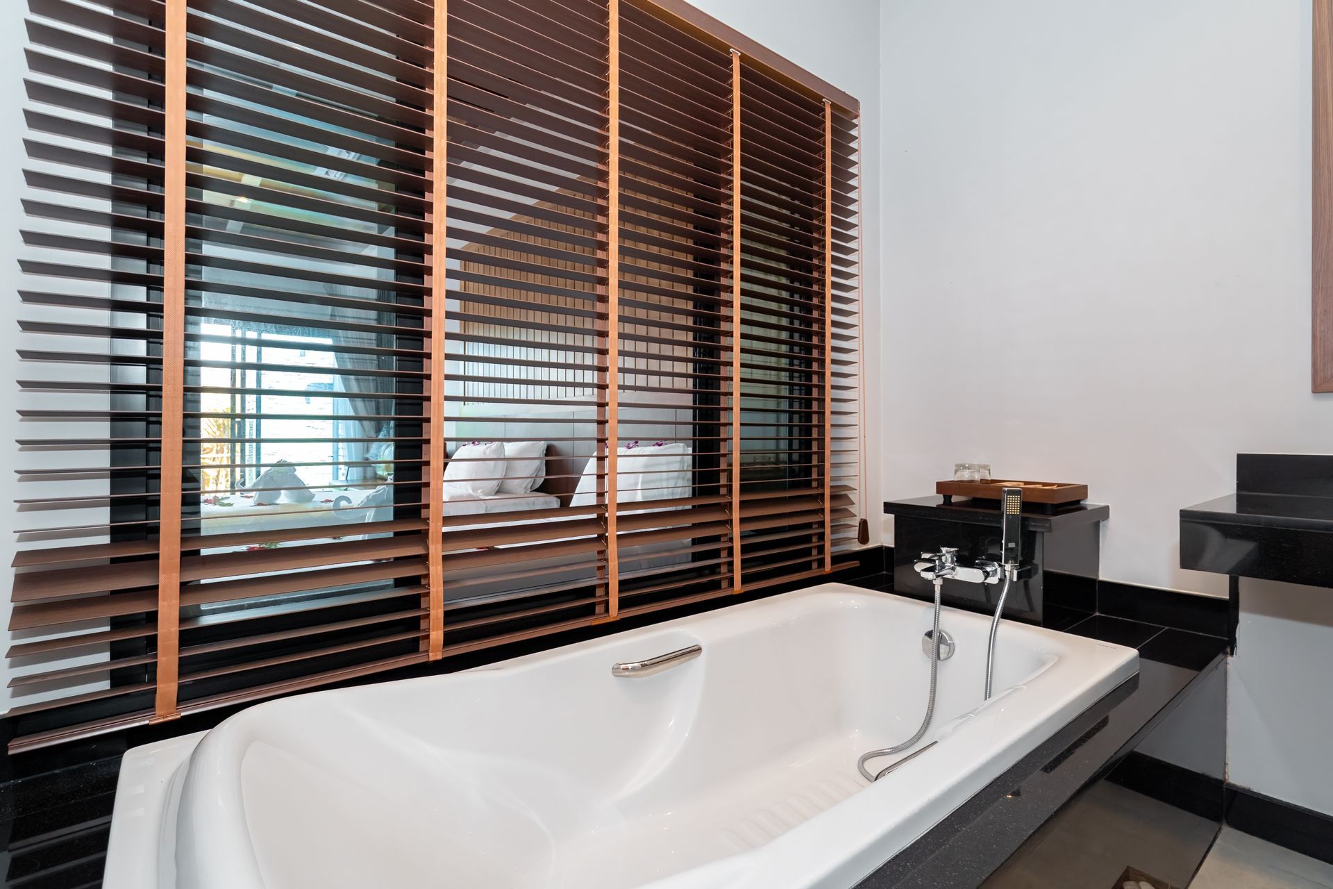 A bathroom with a bathtub and a window with blinds.