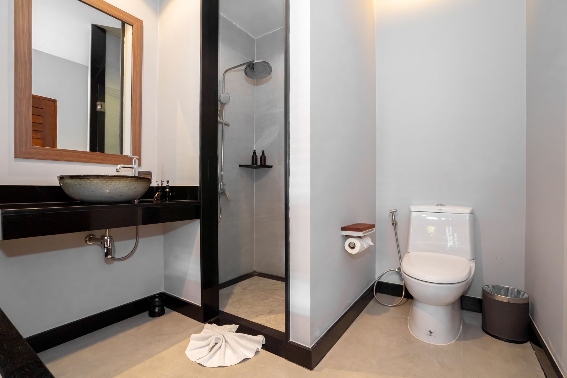 A bathroom with a toilet , sink , mirror and shower.