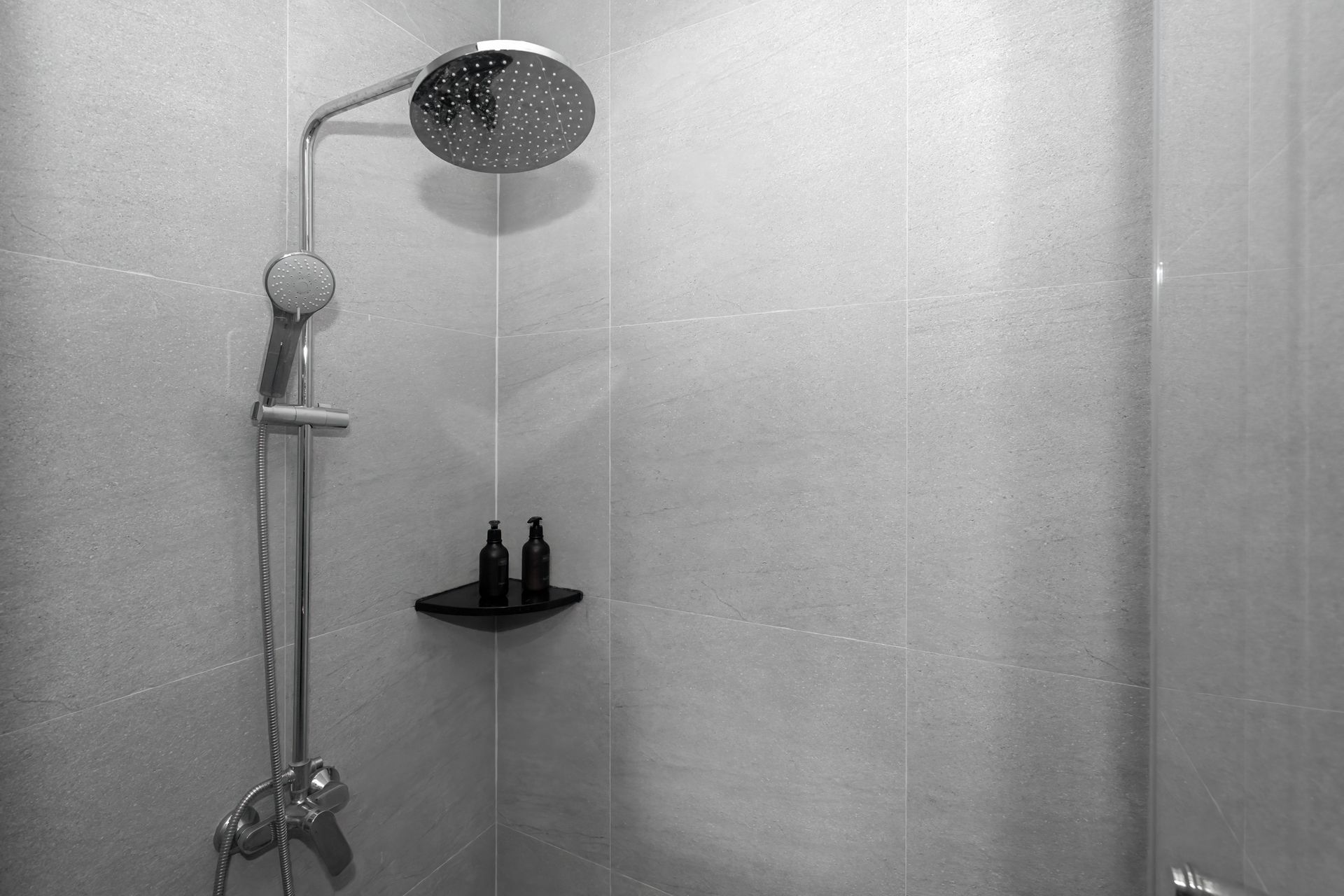 A black and white photo of a shower head in a bathroom.