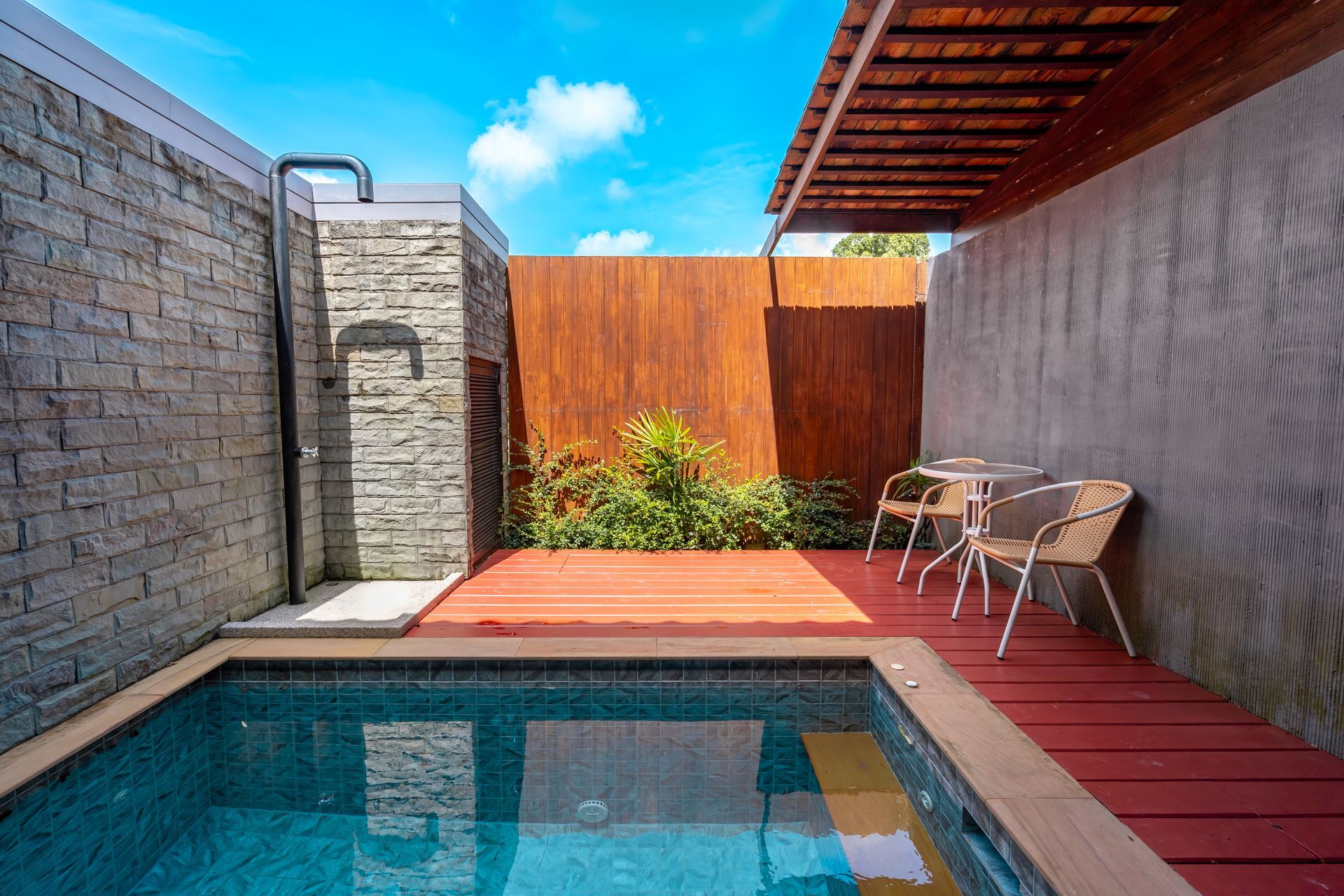 A small swimming pool with a table and chairs next to it.