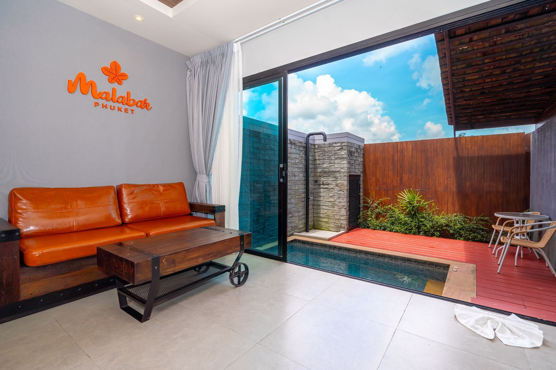 A living room with a couch , table , chairs and a swimming pool.