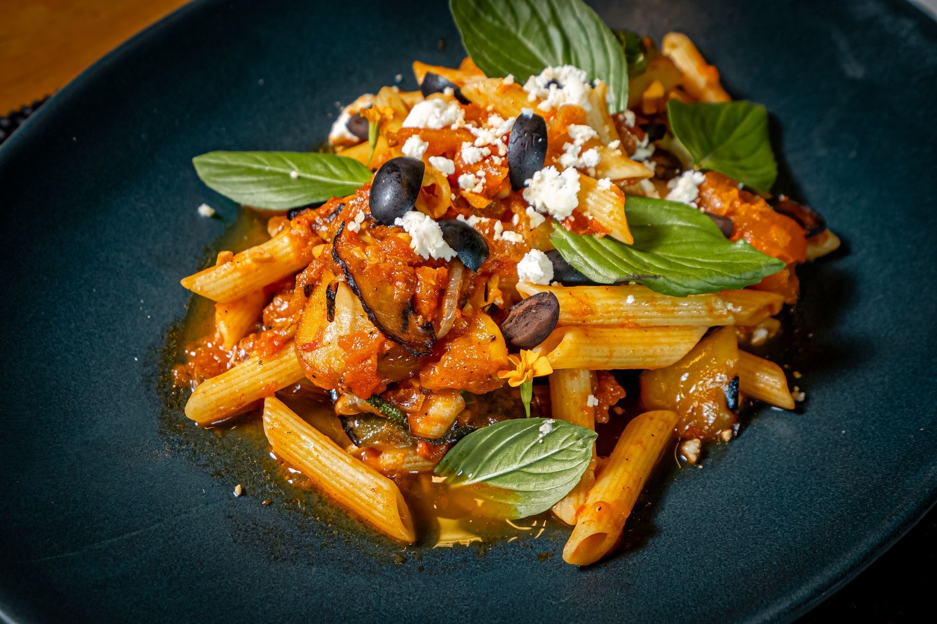 A close up of a plate of pasta with vegetables on a table.