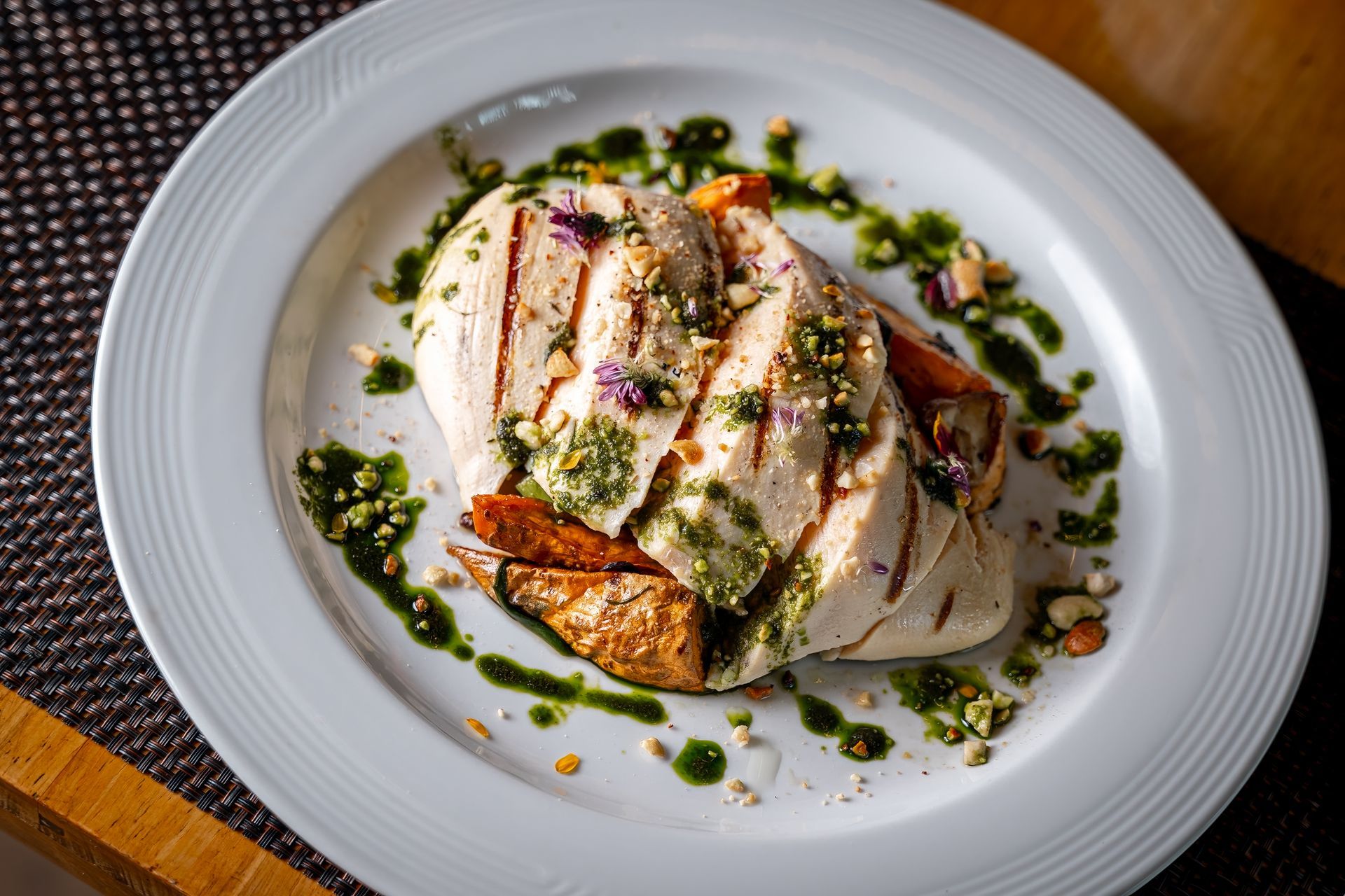 A white plate topped with grilled chicken and vegetables on a table.