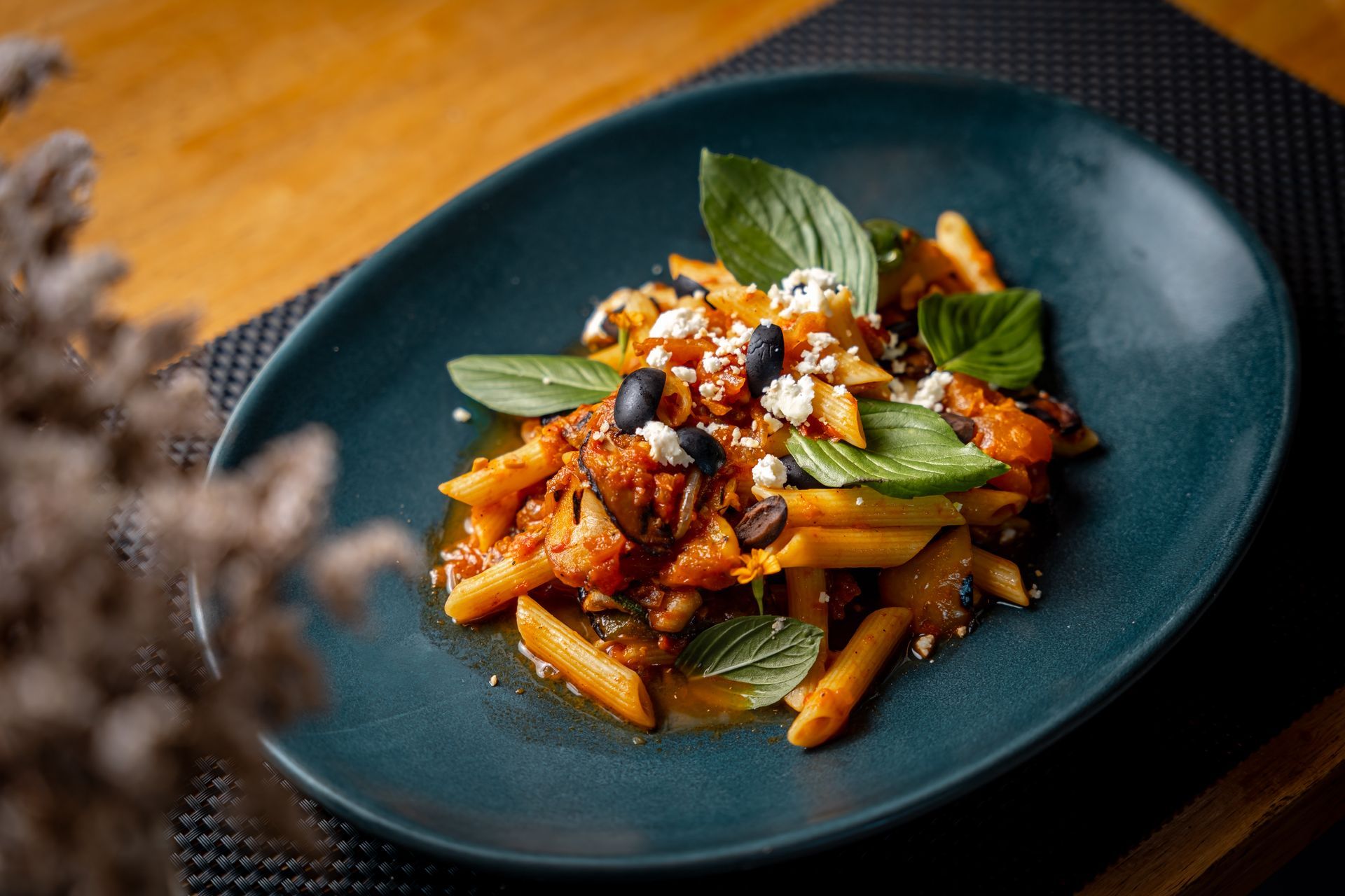 A plate of pasta with tomato sauce and basil on a table.