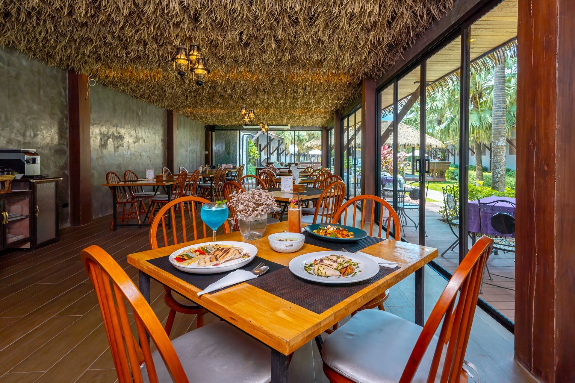 A restaurant with tables and chairs and plates of food on them.