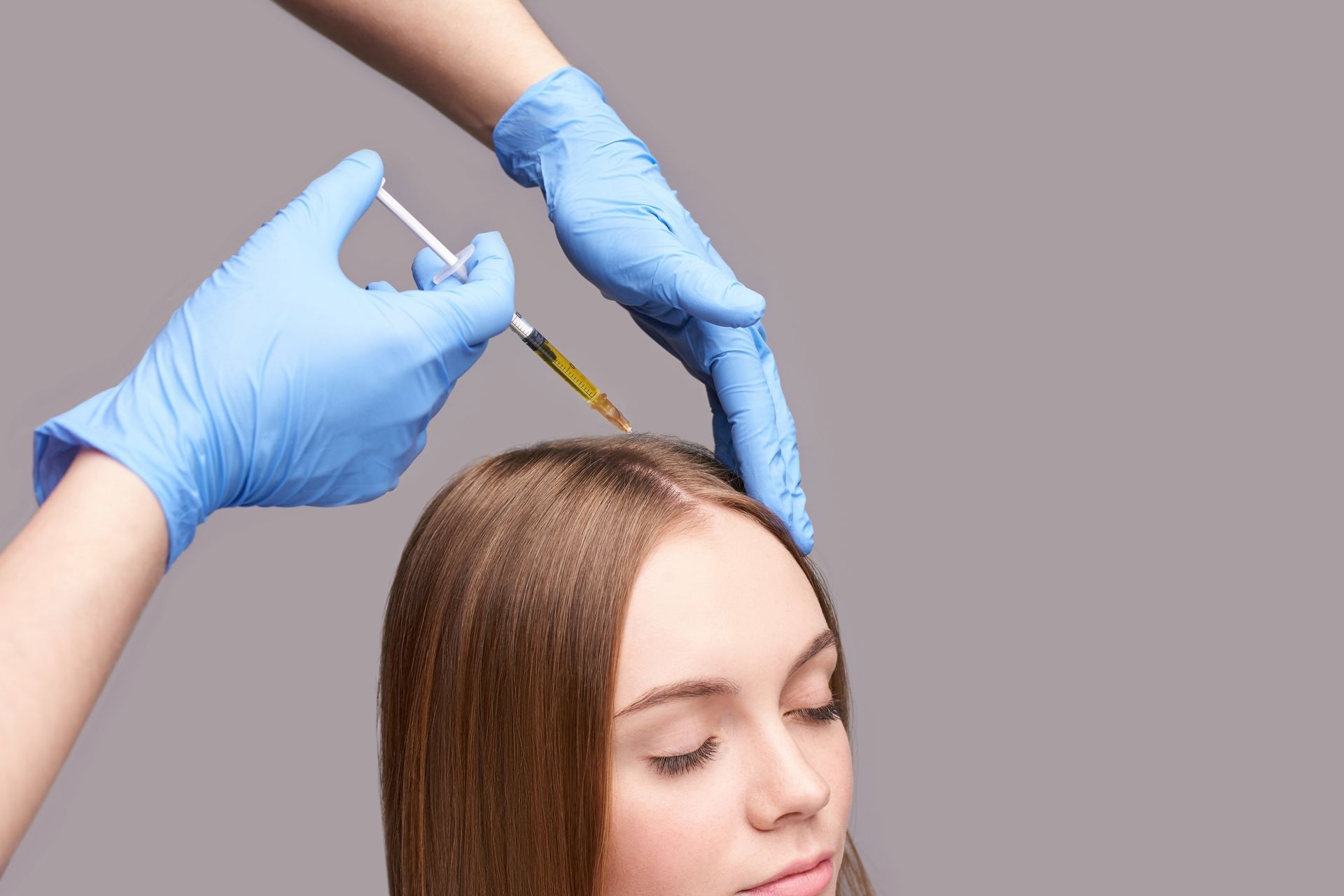 A woman is getting an injection in her hair.