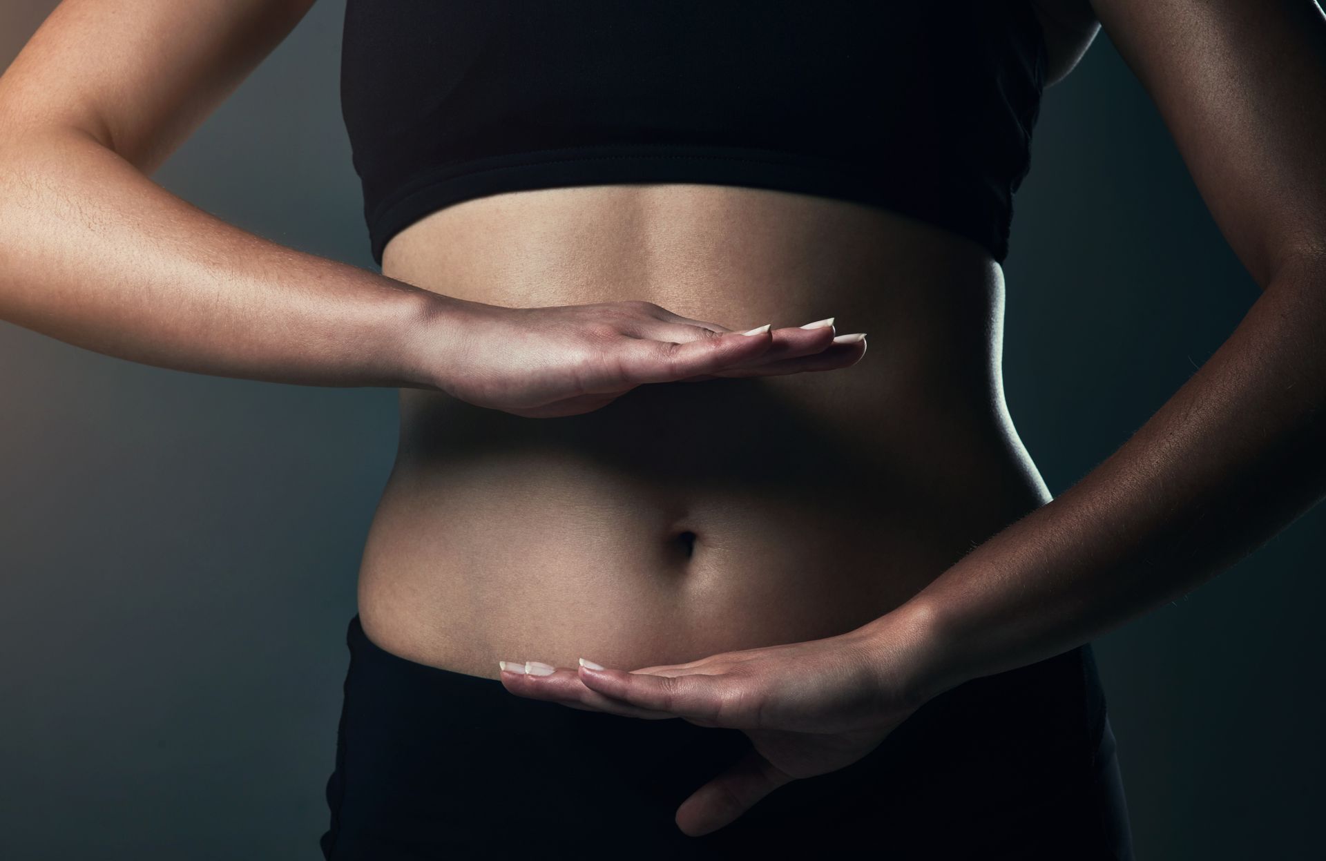 A woman is holding her hands on her stomach.