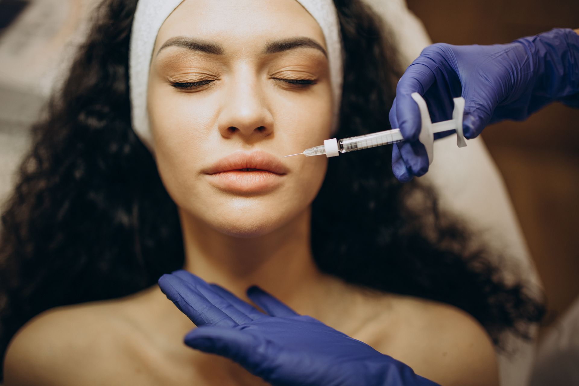 A woman is getting a botox injection in her lips.