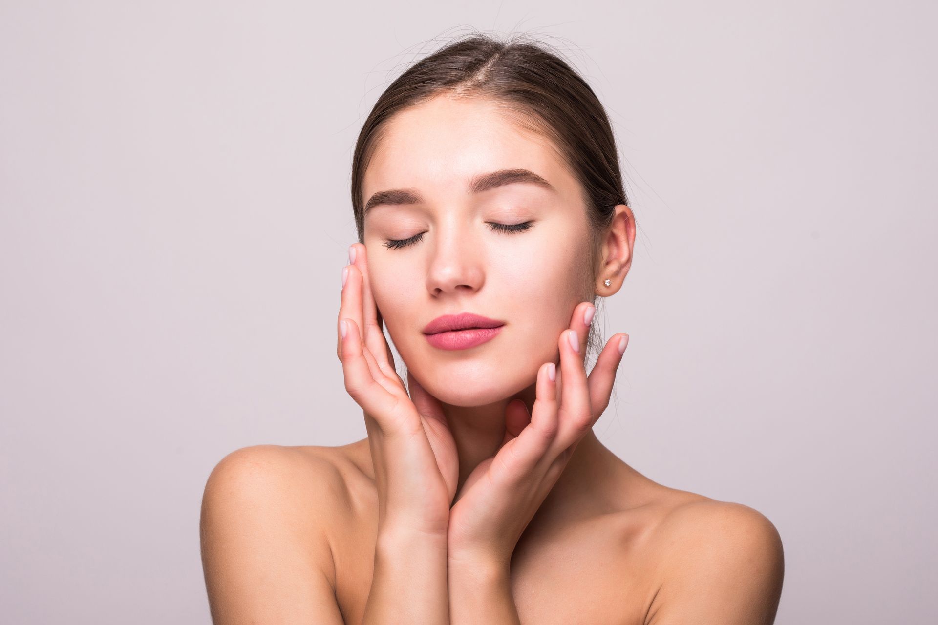 Woman with eyes closed, gently touching her face.