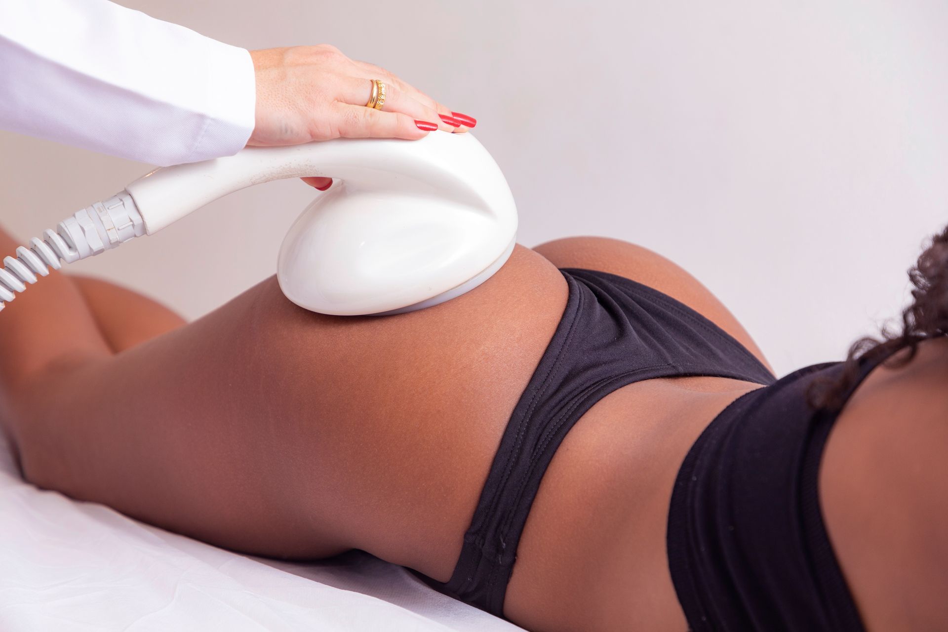 A woman in black underwear is getting a massage from a doctor.