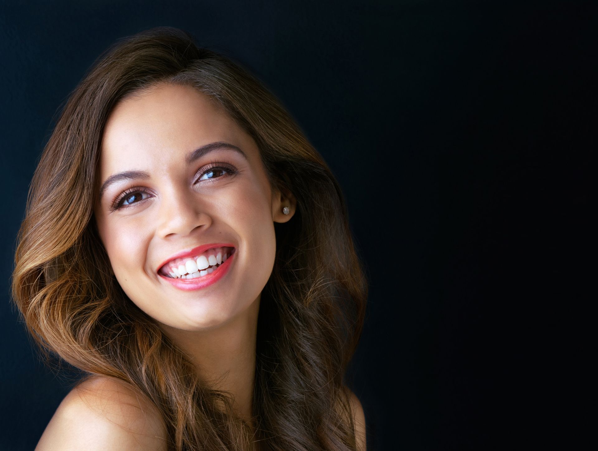 A close up of a woman smiling on a black background.