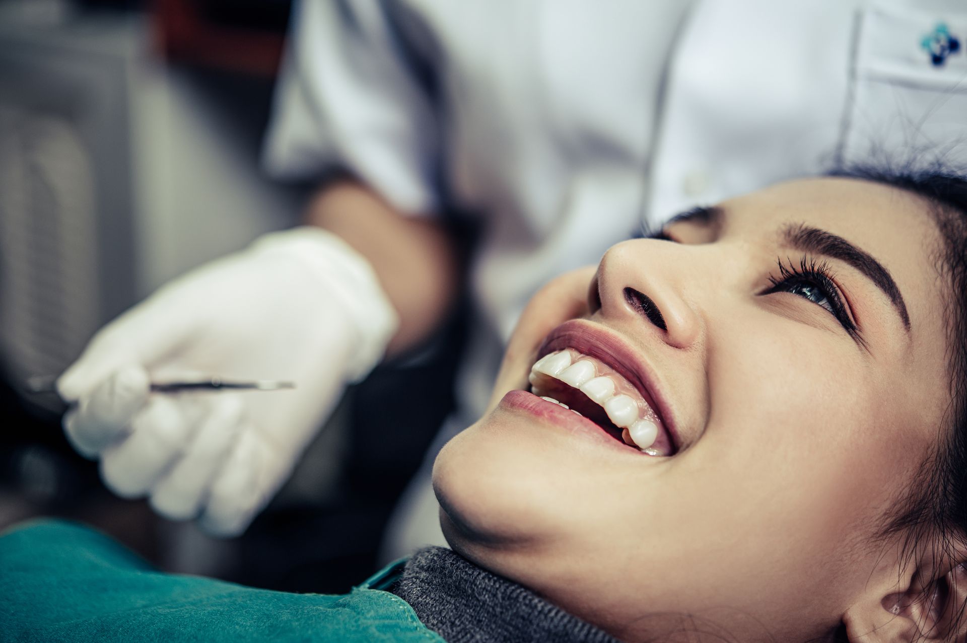 A woman is smiling while having her teeth examined by a dentist.