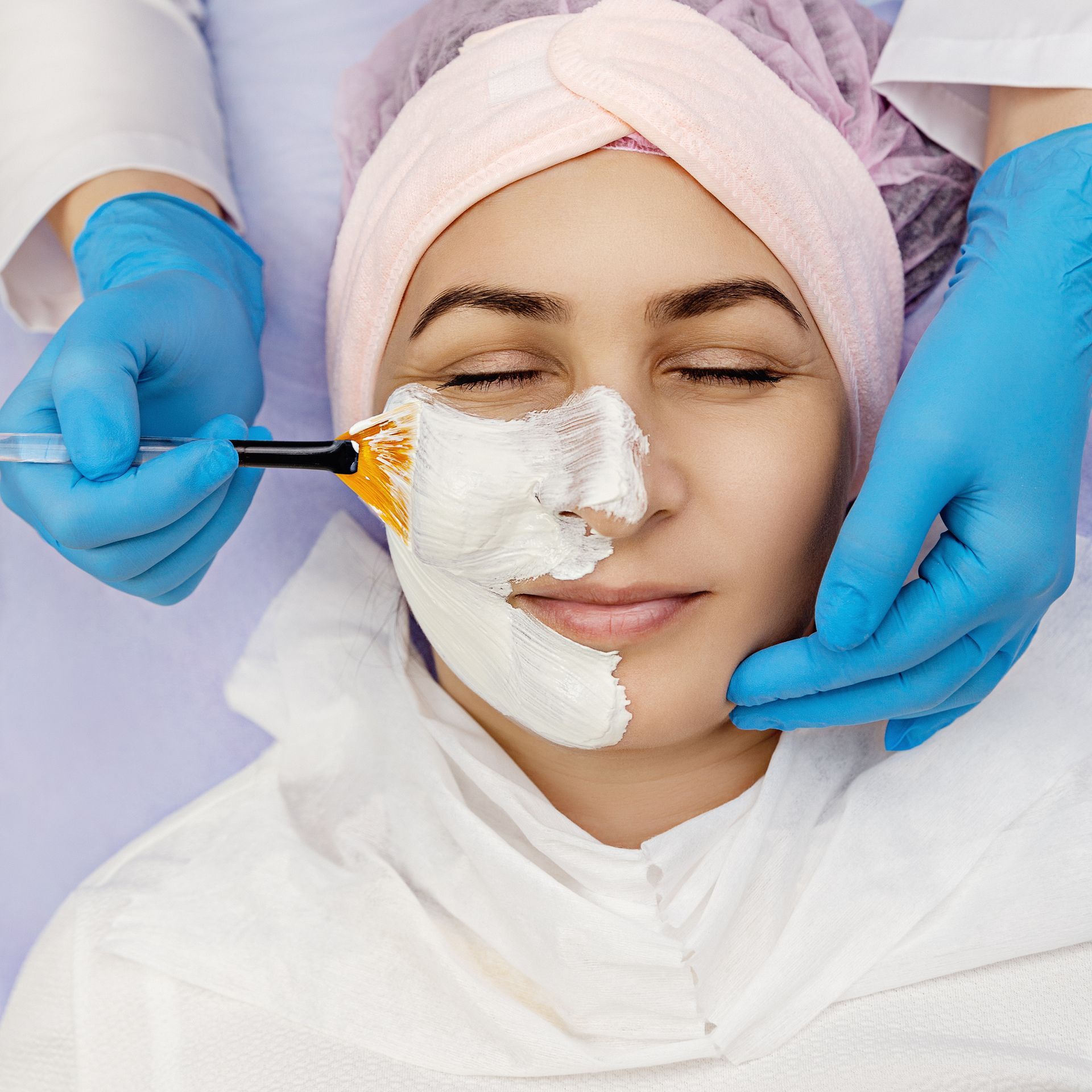 A woman is getting a white mask on her face